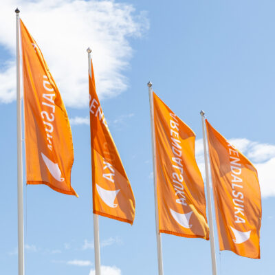 Fire oransje Arendalsuka-bannere mot blå himmel.