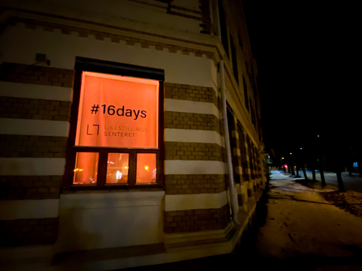 Et vindu er lyst opp med oransje lys. Teksten #16days er synlig i vinduet.